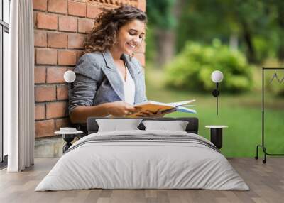 Young caucasian college mixed race student with book in college campus. University student going to college. Wall mural